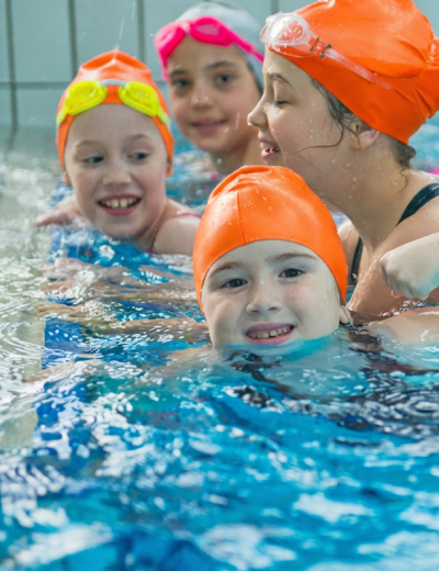 Swimming instructor teaching a small group of children technique in the pool
